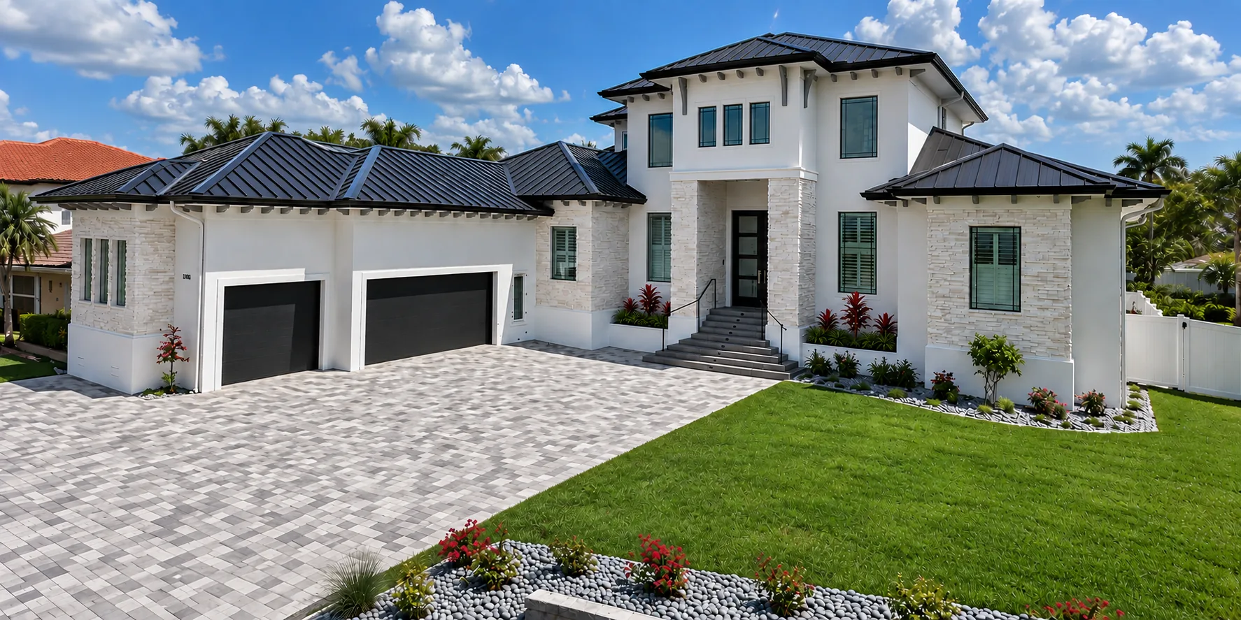 Coastal custom home with stone accents, metal roof and paver driveway