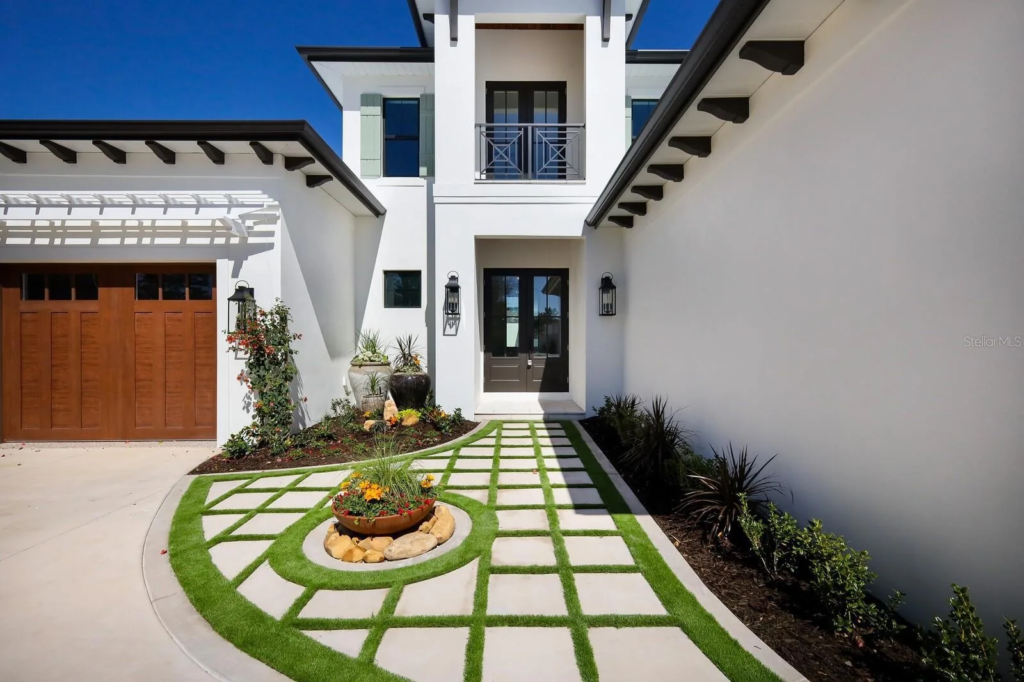 White custom home with courtyard walkway and wood garage doors