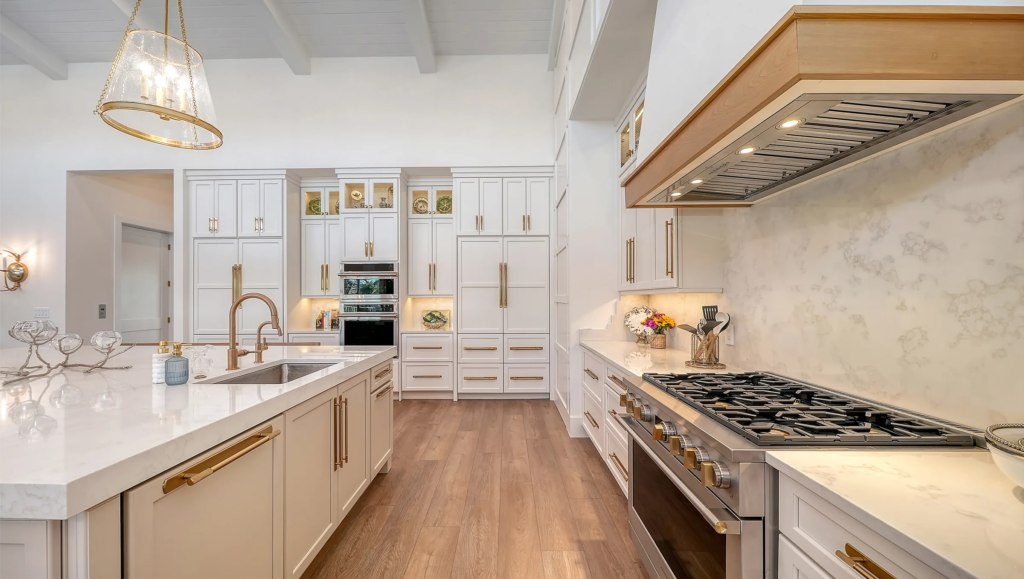 Custom kitchen with gold hardware, wood range hood and marble counters