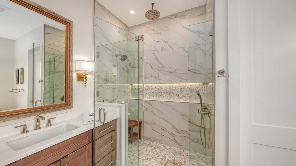 Primary bath with glass walk-in shower and marble tile