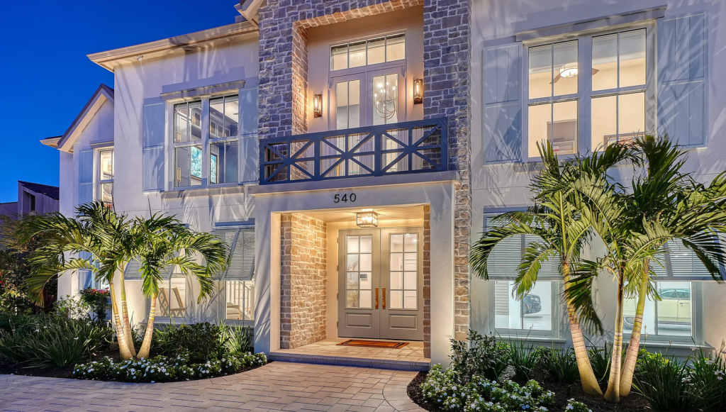 Custom home with stone facade and lit front entry at twilight in Sarasota, Florida
